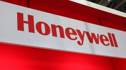 A red and white Honeywell branded sign photographed at an angle inside a busy trade convention center