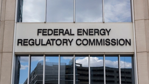 Federal Energy Regulatory Commission sign mounted on a stone building facade beneath tall glass windows