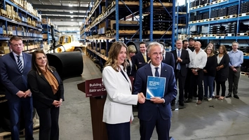A group of professionals looks on as two colleagues shake hands at a Building Canada podium in a warehouse